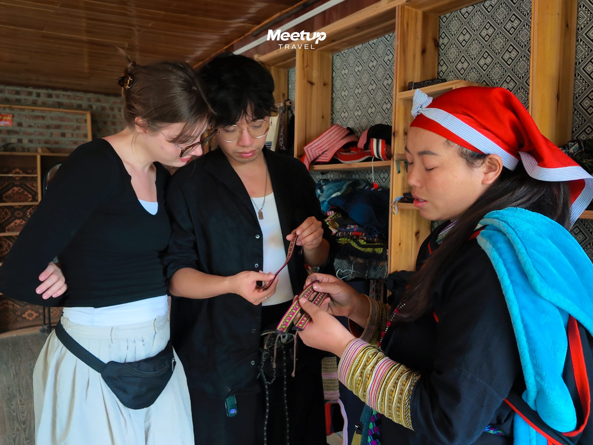 Red Dao woman helping a guest into traditional dress