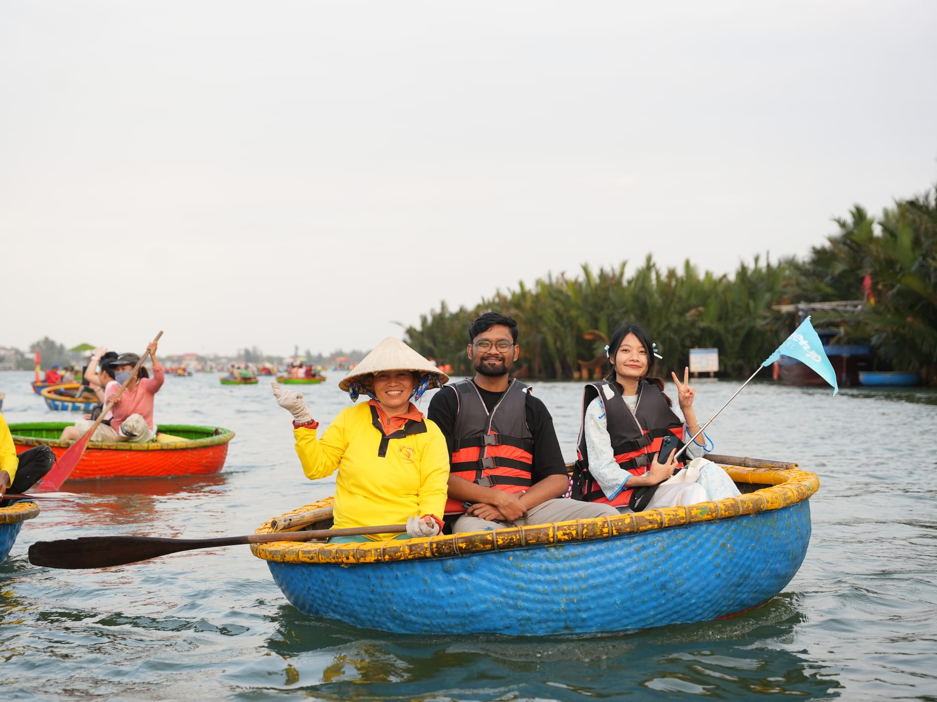 Tourists and a local rower in a basket boat in the coconut palm water forest, Hoi An
