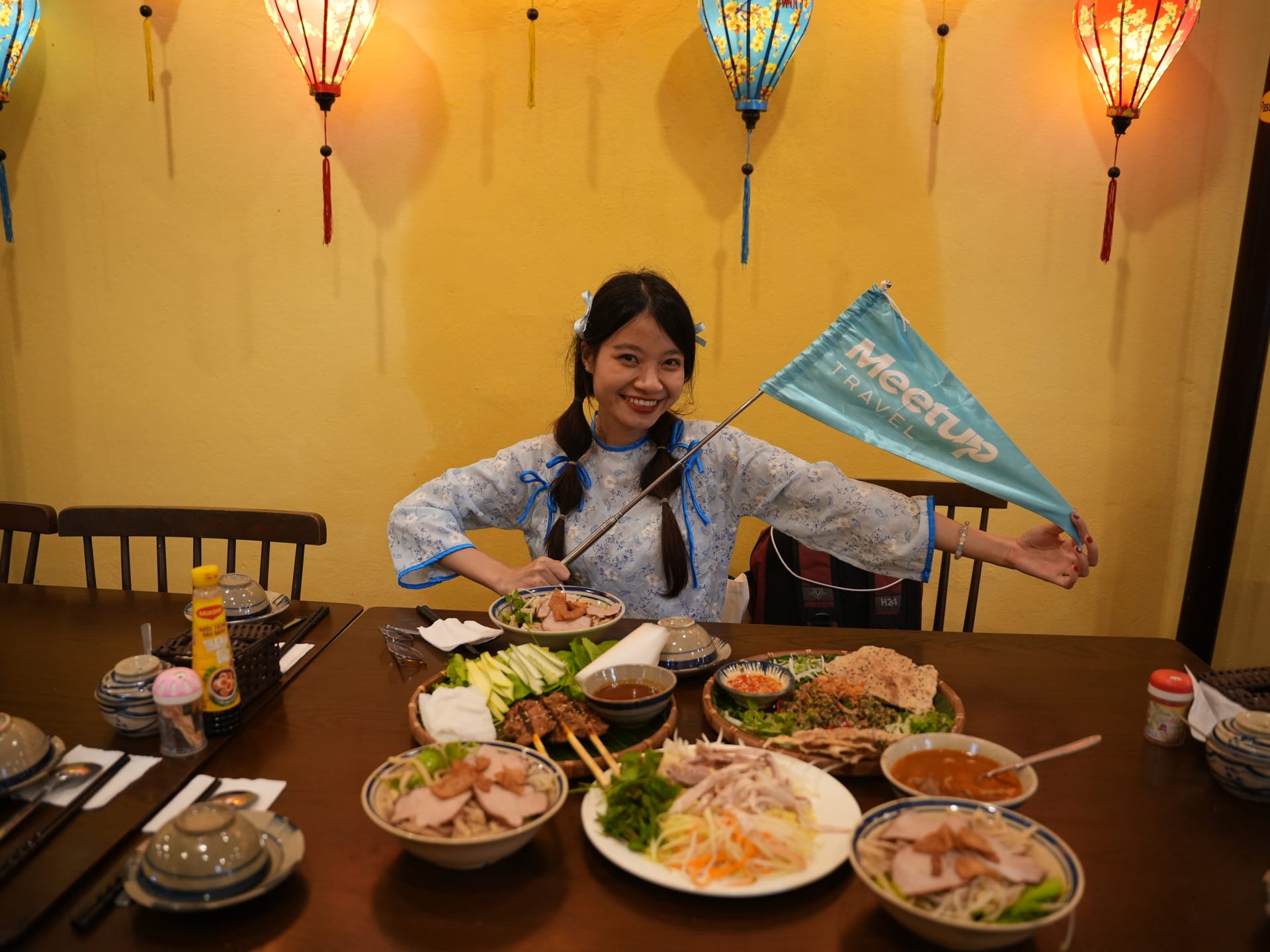 Tour guide with local Vietnamese food spread in a lantern-lit restaurant.
