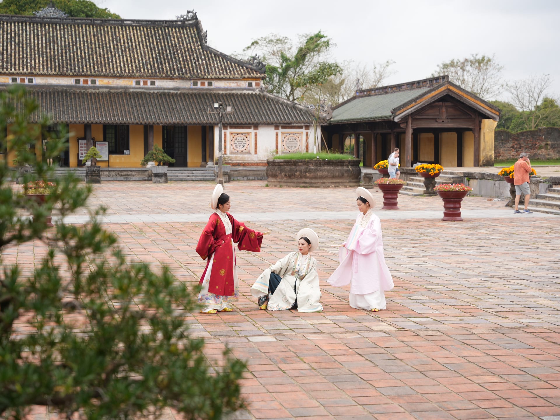 Tourists in traditional Nguyen Dynasty Nhat Binh attire taking photos at Hue Imperial Citadel.