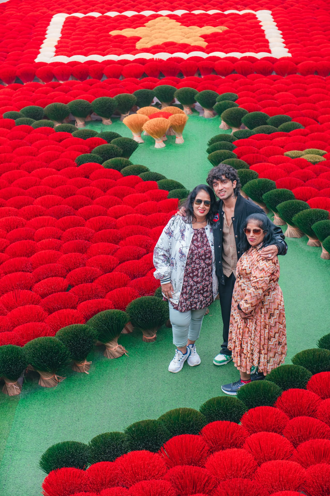Visitors posing on a floral installation shaped like the map of Vietnam