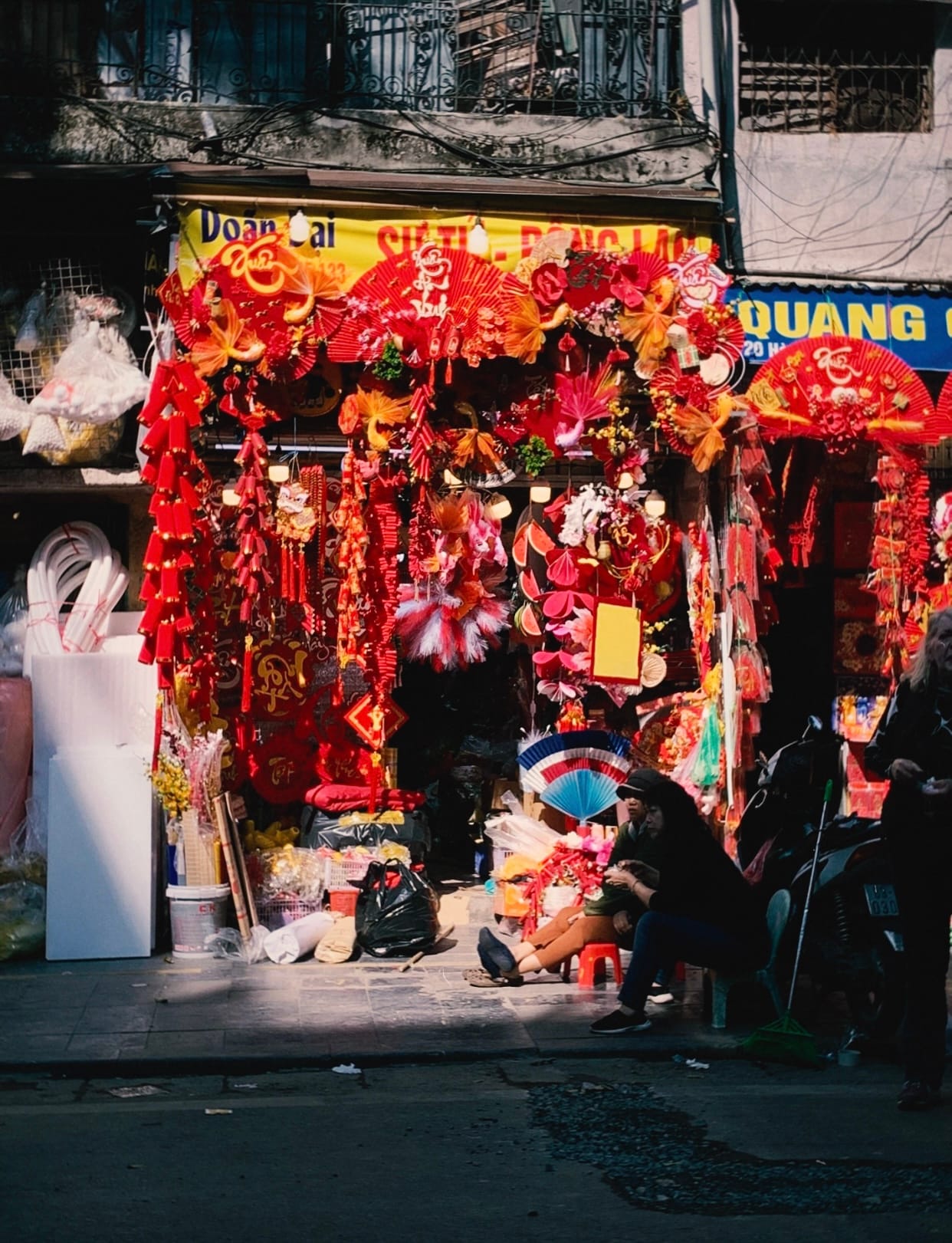 Red paper lanterns and decorations hanging above a crowded lane on Hang Ma Street in Hanoi.