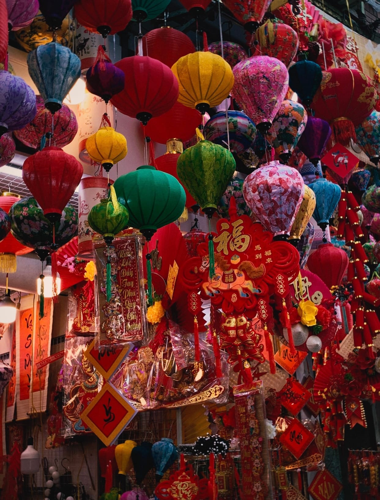 Red paper lanterns and festive goods hang above a crowded Hang Ma Street in the Old Quarter.