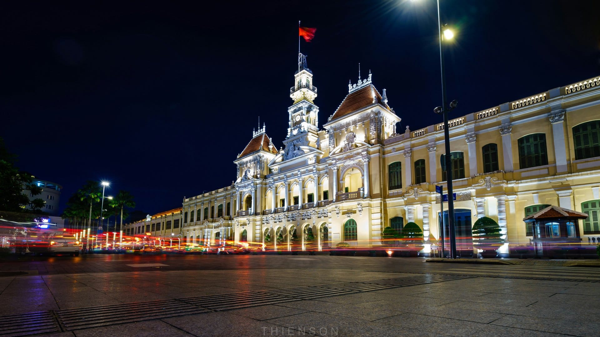 The People's Committee Building in Ho Chi Minh City glows at night with streaks of passing traffic.
