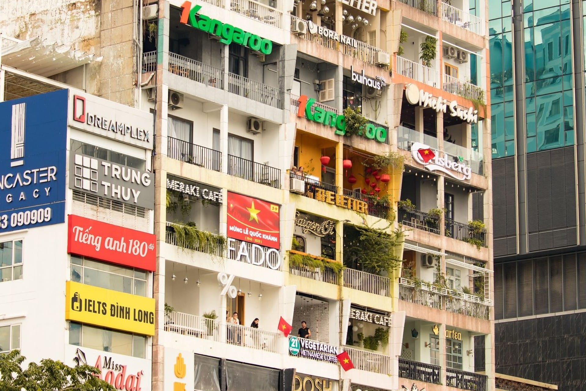 The Cafe Apartment at 42 Nguyen Hue, its balconies stacked with lit shopfront signs