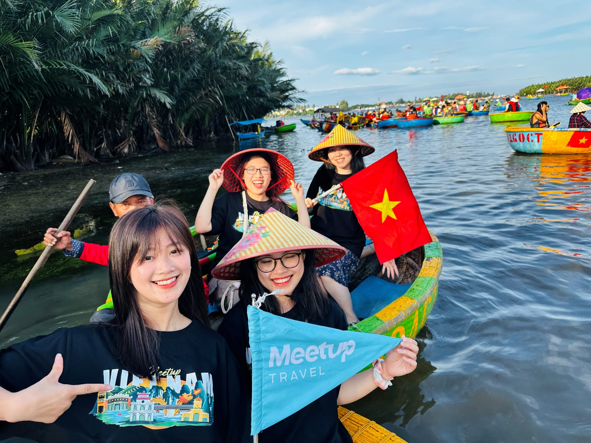 Group of friends holding Vietnam flag on Hoi An basket boat
