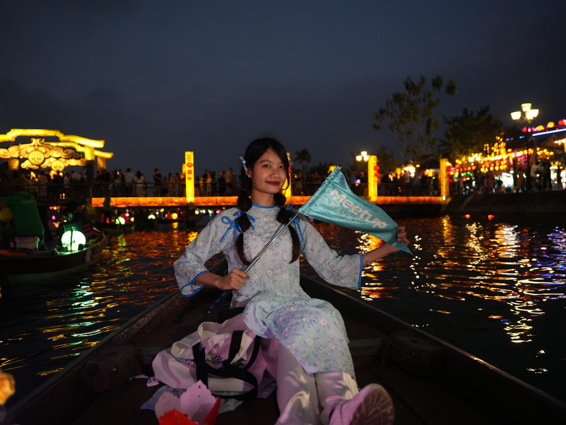 Woman in traditional dress on a lantern boat at night in Hoi An